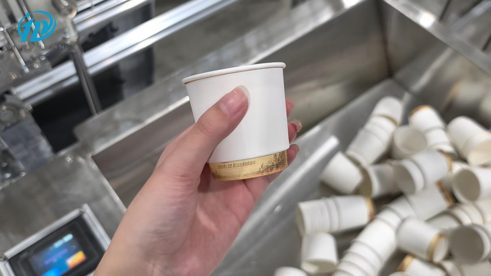 Completed 4 oz cup with a white outer sleeve beside the collection area